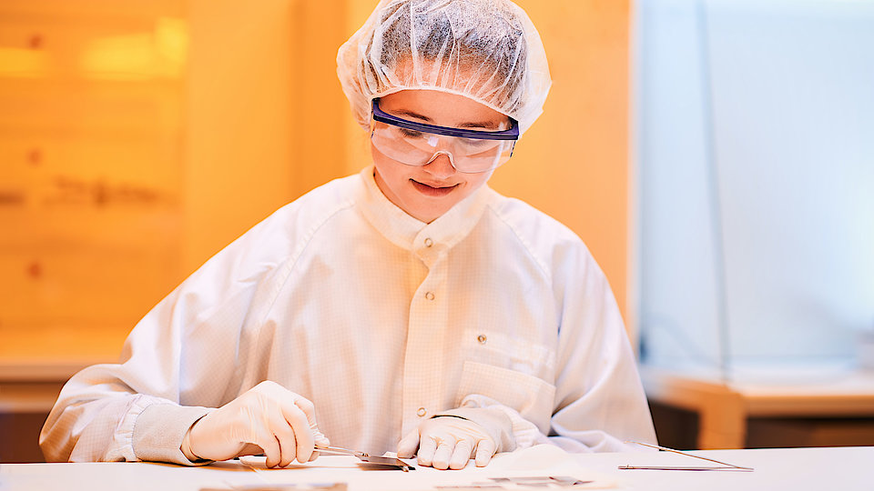 Auszubildende zerteilt einen großen Wafer.